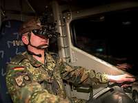 Ein Soldat mit Nachtsichtbrille sitzt am Steuer eines Fahrzeugs.