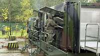 Two CBRN defense soldiers are working on a special container