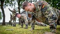 Soldaten machen Liegestütz in Uniform auf einer Wiese