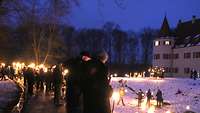 Teilnehmer der Waldweihnacht mit Fackeln vor dem Schloss