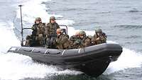 Mehrere Soldaten sitzen in einem Speedboot