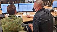 Ein Soldat und ein ZIvilist sitzen vor dem Computer.