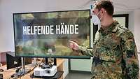 Ein Soldat im Dienstgrad des Feldwebels hält eine Präsentation über die Helfenden Hände.