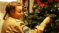 Eine Soldatin schmückt einen Weihnachtsbaum