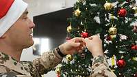Soldaten schmücken einen Weihnachtsbaum mit Kugeln und Engeln.