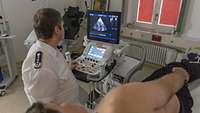 Ein Arzt untersucht einen Bewerber mittels Ultraschallgerät.