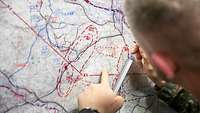 Soldat zeichnet ein Lagebild ein einer Karte