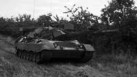 Schwarz-Weiß-Aufnahme: Ein Kampfpanzer Leopard steht im freien Gelände.