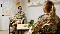 Zwei Soldatinnen im Gespräch in einem Raum. Beide sitzen auf einem Stuhl am Tisch