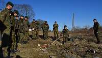 Soldaten stehen am Rand eines Geländemodells, ein Soldat hockt mit einem Zeigestock mittendrin.