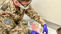 Ein Truppenarzt verbindet eine Hand