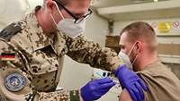 Ein Truppenarzt impft einen Soldaten