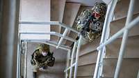 Zwei bewaffnete Soldaten mit Treppenhaus eines Gebäudes