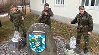 Drei Männer in Uniform der Bundeswehr stehen vor einem Haus.