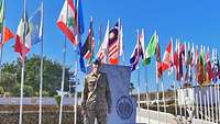 Ein Soldat steht vor dem Eingangsbereich des Naval Operations Center im Libanon, hinter ihm viele Flaggen 