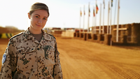 Eine Soldatin im Camp Castor vor internationalen Flaggen
