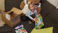 Ein Mädchen freut sich über Lego Duplo als Geschenk. 