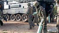 A self-propelled howitzer with its rear door open; Hungarian soldiers are heaving the artillery rounds to the howitzers by hand.