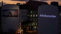 Leuchtender Schriftzug #WeRemember an der Hausfassade des Verteidigungsministeriums