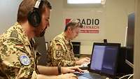 Zwei Soldaten sitzen vor ihren Computern. Der vordere Soldat trägt Kopfhörer. 