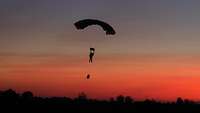 Im Abendrot gleitet ein Fallschirmspringer durch den Himmel. 