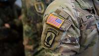 Ein amerikanischer Soldat mit der US-Flagge und einen „Airborne“-Abzeichen auf dem Arm.