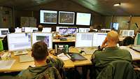 Blick von hinten über Soldaten und Computer in eine Operationszentrale.