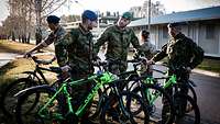 Fünf Soldaten stehen mit Fahrrädern am Rande einer Straße
