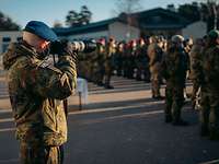 Ein Soldat fotografiert von hinten die in einer Formation angetreten Soldatinnen und Soldaten