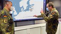 Zwei Soldaten stehen vor einer Europakarte.