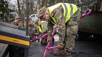 Soldaten verzurren Fahrzeuge auf der Ladefläche eines Sattelaufliegers