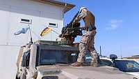 Ein Soldat steht auf dem Dach eines Einsatzfahrzeuges und kontrolliert das Waffensystem