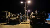 Im Dunkeln werden zwei Gefechtsfahrzeuge an einer militärischen Tankstelle betankt.