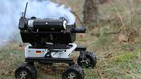 Ein kleiner Roboter auf Rädern im Gelände stösst Rauch aus.