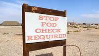 Ein Hinweisschild mit der Aufschrift „Stop FOD Check Required“, im Hintergrund Wüstenlandschaft