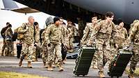 US-Soldaten verlassen mit ihrem Marschgepäck über die geöffnete Heckklappe ein Flugzeug. 