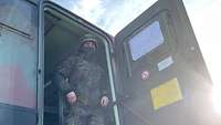 Ein Soldat mit Helm verlässt eine militärische Funkanlage in einem Container.