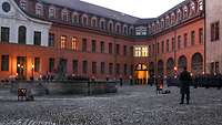 Viele Soldaten stehen mit Fackeln in Formation in einem Schlosshof.