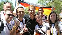 Prinz Harry lächelt mit deutschen Fans im Arm