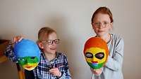 Zwei Kinder mit ihren selbst gestalteten Masken