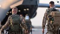 Soldaten mit Gepäck auf dem Weg zu einem geöffneten Transportflugzeug