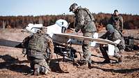Drei Soldaten montieren die Baugruppen der LUNA-Drohne an dem Katapultstartgerät. Im Hintergrund steht ein weiterer Soldat.