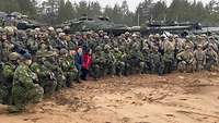 Gruppenfoto: Soldaten aus mehreren Nationen, darunter zwei Zivilisten, vor ihren Fahrzeugen