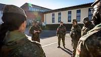 In der Kaserne stehen Soldaten im Halbkreis, ein mittig stehender Soldat erklärt etwas.