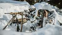 Zwei Soldaten hocken mit Fernglas und Maschinengewehr MG5 in Stellung im Schnee