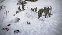 Viele Soldaten bauen im Tiefschnee ein Iglu auf einer Waldlichtung.