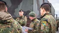 Soldiers listen to a briefing in front of the vehicles.