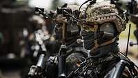 Armed soldiers wearing helmets and radio headsets stand next to one another.