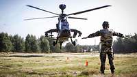 Ein Soldat weist mit Handzeichen einen landenden Hubschrauber ein.