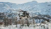 Ein Transporthubschrauber CH-53 fliegt vor einer verschneiten Berglandschaft